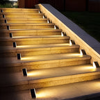 Clérachic step lights lit along a long flight of stone garden steps at night.