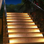 The Clérachic step lights washing warm light across stone stairs beside a black handrail.