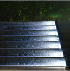 Clérachic step lights lit in cool white along wet stone steps at night.
