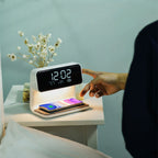 Clérachic bedside station on a white table, a finger touching the display beside two phones.