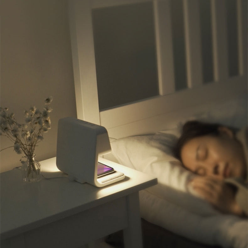Clérachic bedside station glowing softly on a nightstand while someone sleeps beyond.