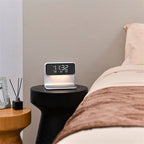 The Clérachic bedside station lit on a round black side table next to a made bed.