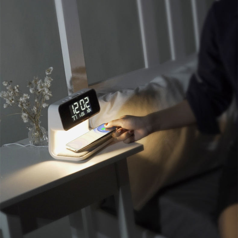 A hand placing a phone on the Clérachic bedside station's charging pad in a dim bedroom.