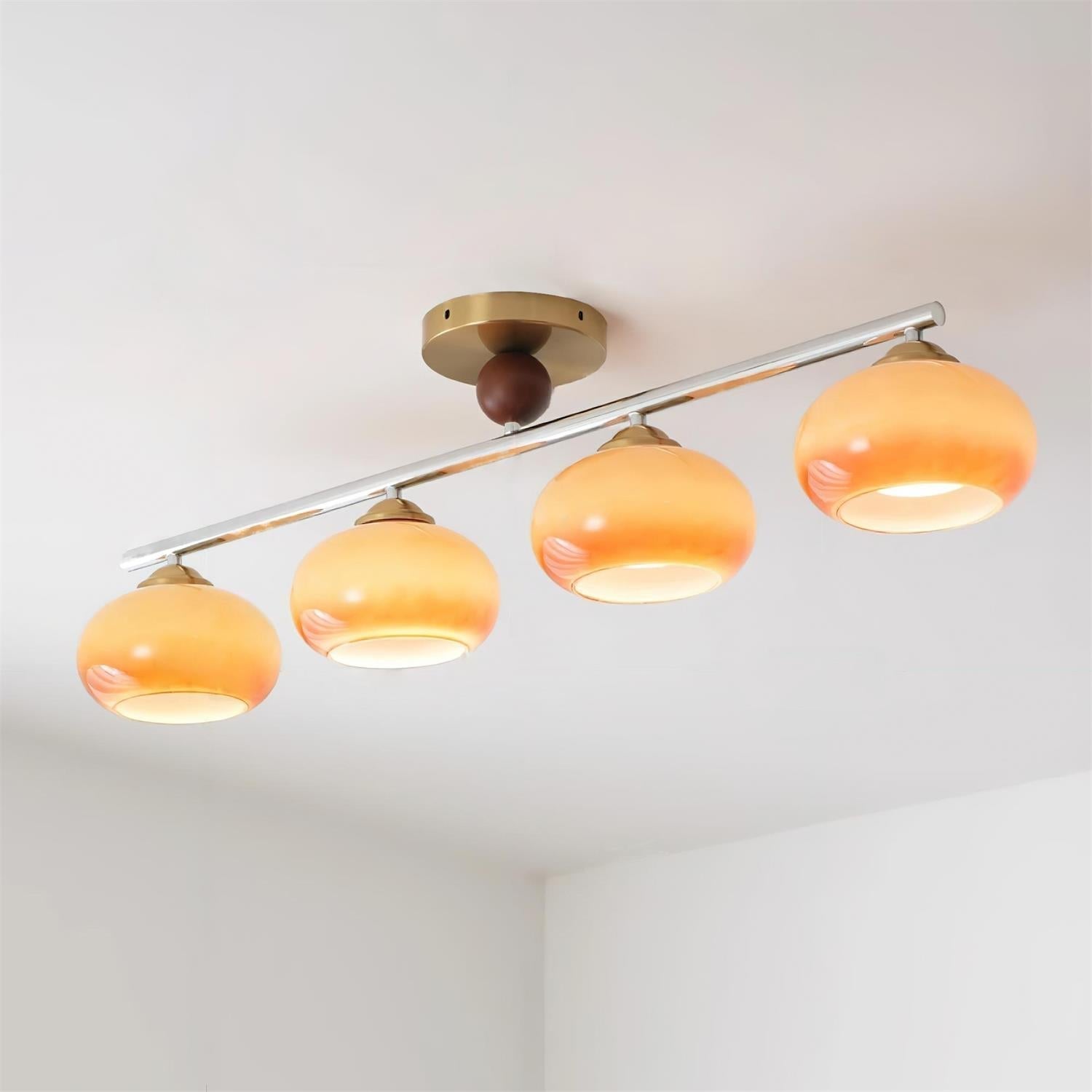 Clérachic 4-Dome Glass Bar Ceiling Light in caramel glass, all four domes lit warm amber along a chrome bar on a white ceiling.