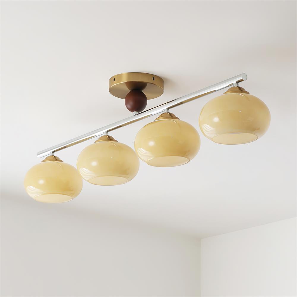 The beige option of the Clérachic 4-Dome Glass Bar Ceiling Light, unlit, its oatmeal-cream domes stepping down a polished chrome bar.