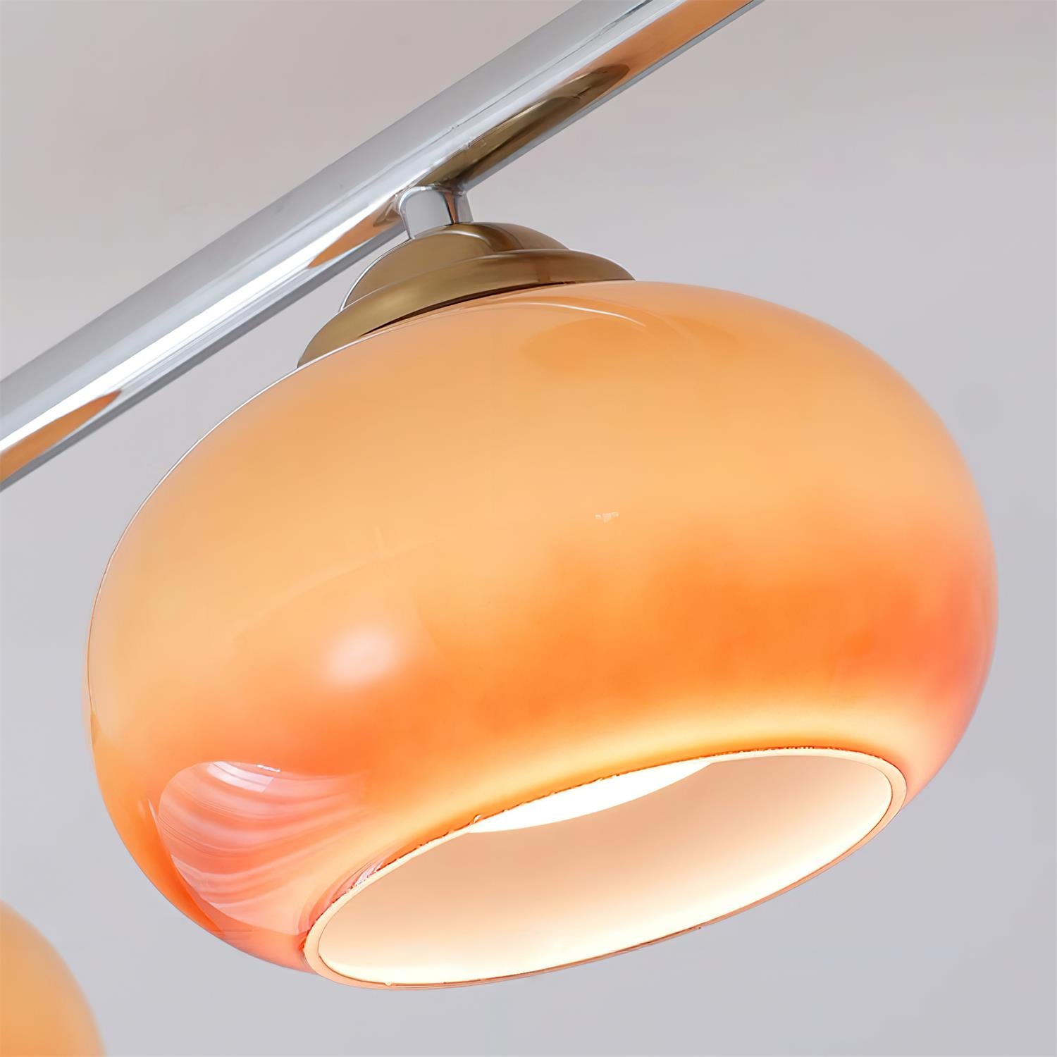 Close-up of one caramel dome on the Clérachic 4-Dome Glass Bar Ceiling Light, lit through the open base with the pink swirl in the glass.