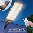 The Clérachic solar street light lit brightly, its tilting solar panel and remote alongside.
