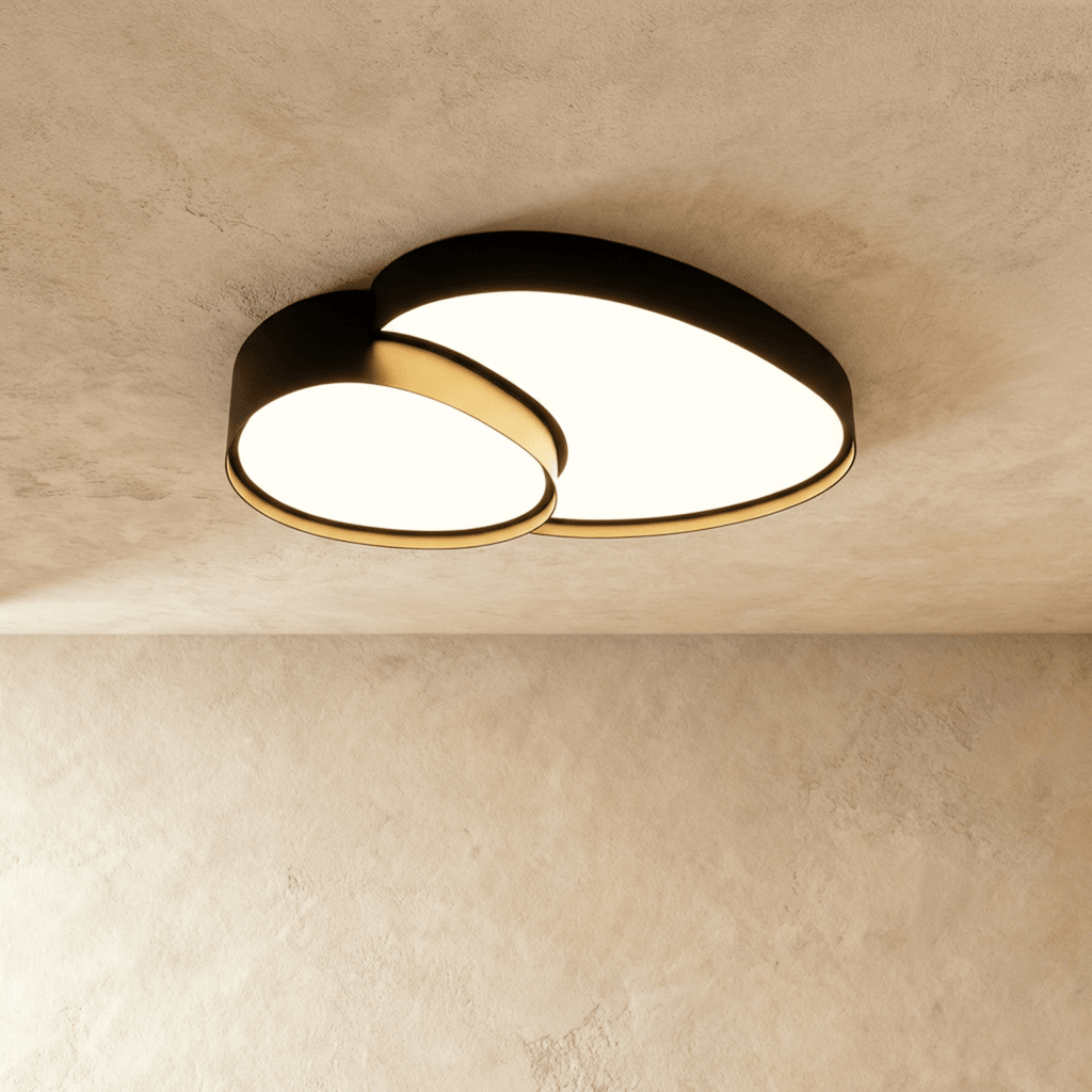 Clérachic matte black overlapping-disc ceiling light, lit warm white, mounted flush against a plastered living room ceiling.