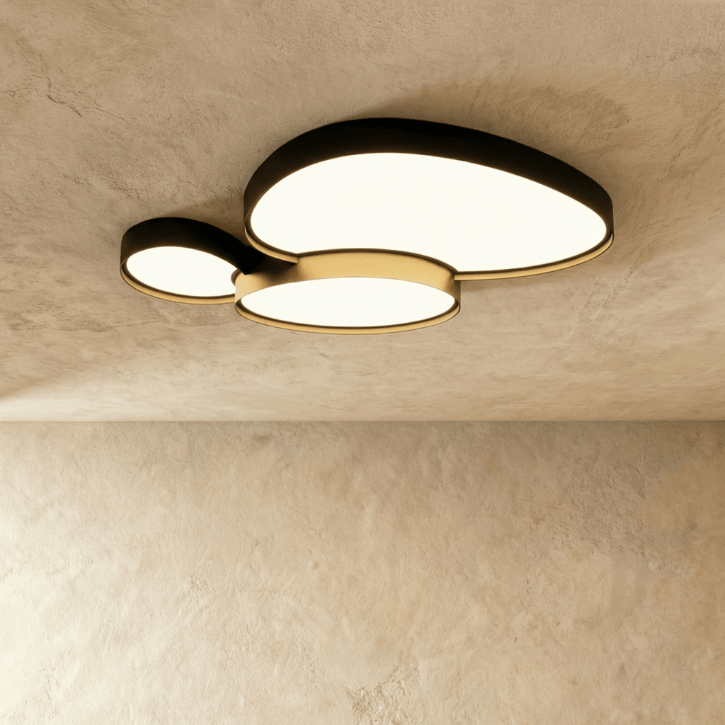 The Clérachic black ceiling light seen from below, two overlapping oval discs casting a soft warm white glow across the room.