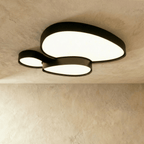 Close overhead angle of the Clérachic black overlapping-disc ceiling light, acrylic diffusers lit warm white against a textured ceiling.