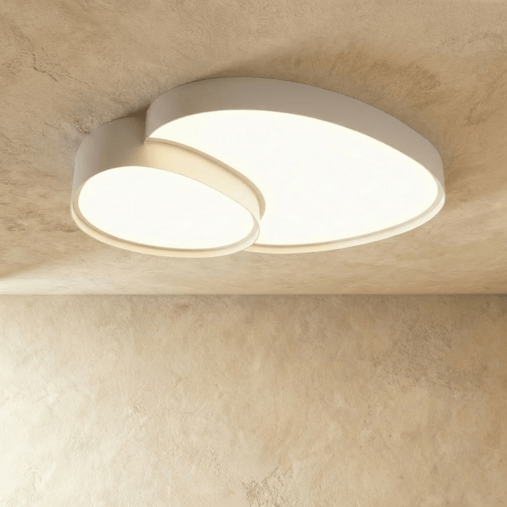 Side angle of the Clérachic white overlapping-disc ceiling light, its acrylic panels lit warm white in a minimalist room.