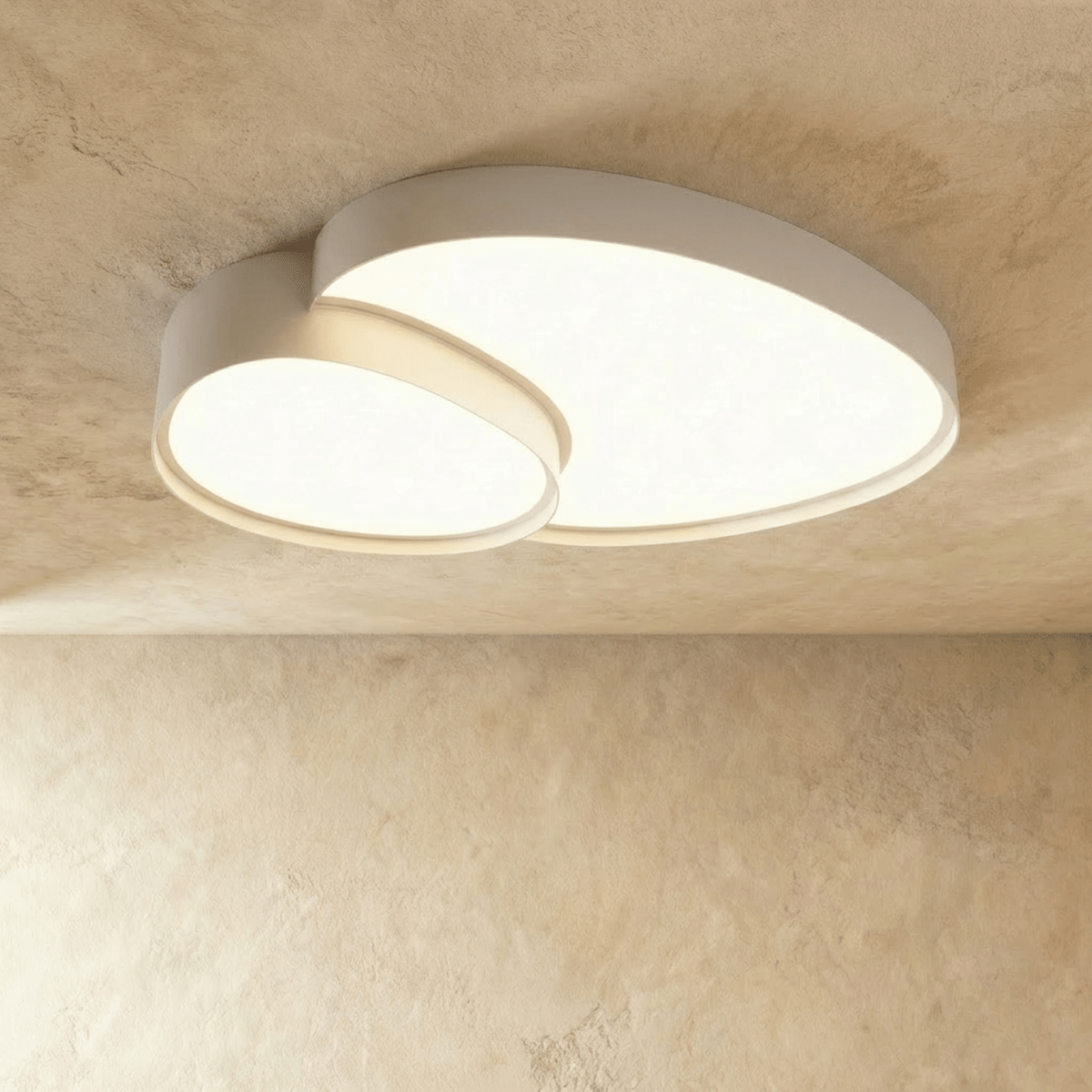Side angle of the Clérachic white overlapping-disc ceiling light, its acrylic panels lit warm white in a minimalist room.