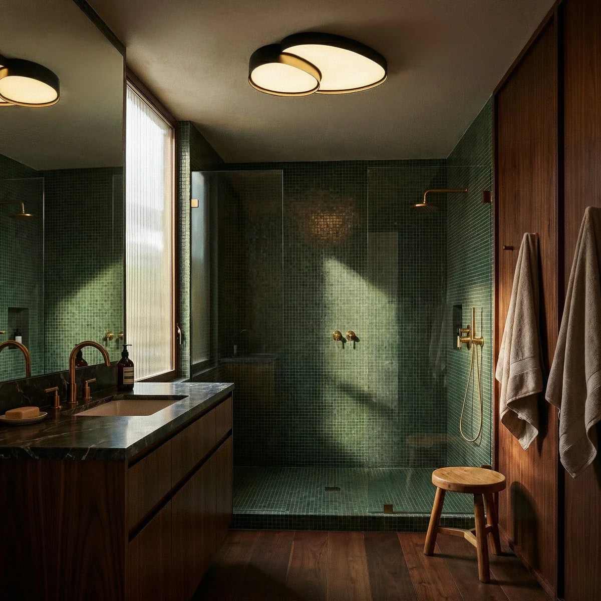Wide bathroom view showing the Clérachic black ceiling light overhead, its warm white glow reflected in the vanity mirror.