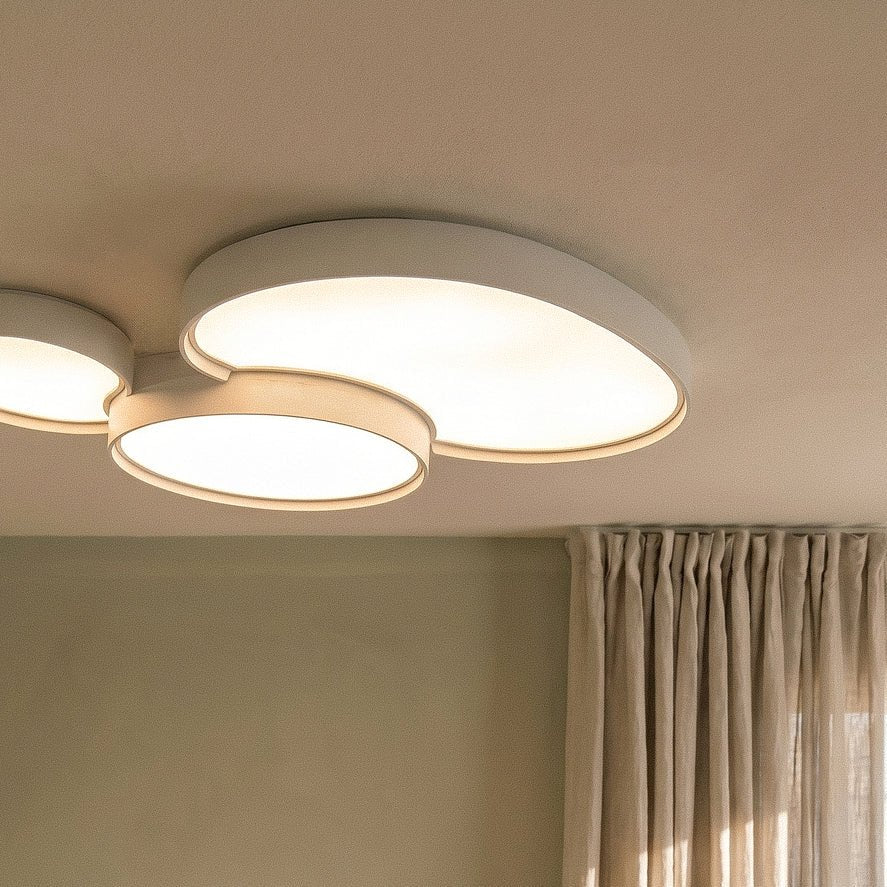 Close crop of the Clérachic white overlapping-disc ceiling light, its acrylic panels glowing warm white overhead.