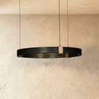 Clérachic ring chandelier, a single black perforated-metal ring with brass mounts, hung from a plaster ceiling.
