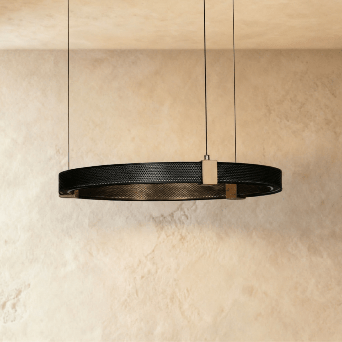 Clérachic ring chandelier, a single black perforated-metal ring with brass mounts, hung from a plaster ceiling.