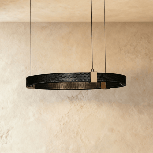 Clérachic ring chandelier, a single black perforated-metal ring with brass mounts, hung from a plaster ceiling.