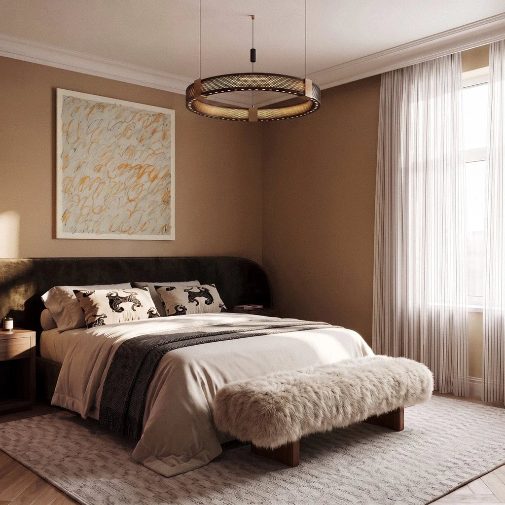Clérachic single-ring chandelier lit warm over a bed, its perforated black band on slim brass-topped cables.