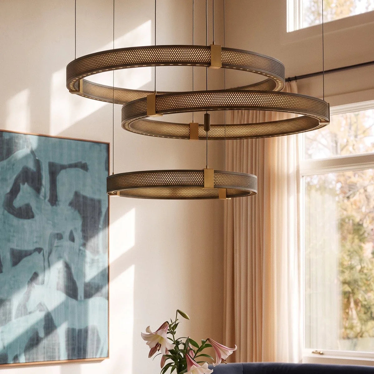 Clérachic three-tier ring chandelier detail, close-up on the perforated black bands and brass tier connectors.