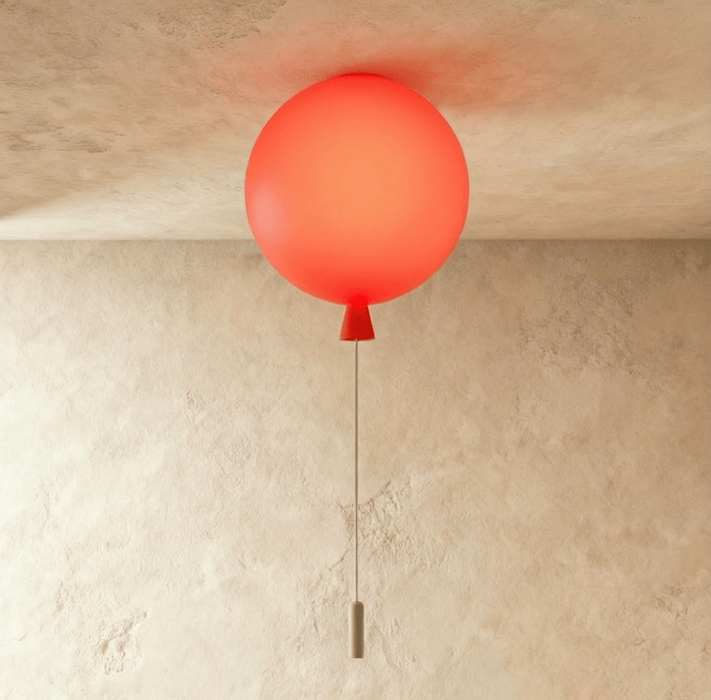 Clérachic balloon-shaped ceiling light glowing coral red, with a red cone neck and a thin pull cord, against a textured plaster wall.
