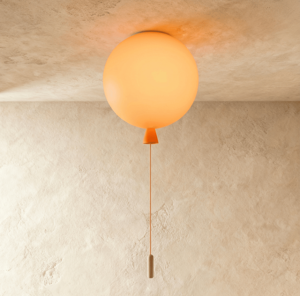 Clérachic balloon-shaped ceiling light glowing soft orange, with an orange cone neck and cord, fixed to a plaster ceiling.