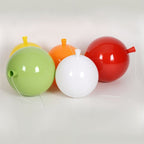 Clérachic glossy balloon lamp globes in green, yellow, orange, white and red laid on their sides, showing the cone necks and cords.