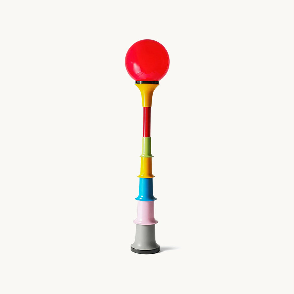 Red glass globe on a stacked column of multicolour tiers, this Clérachic floor lamp on a plain off-white backdrop.