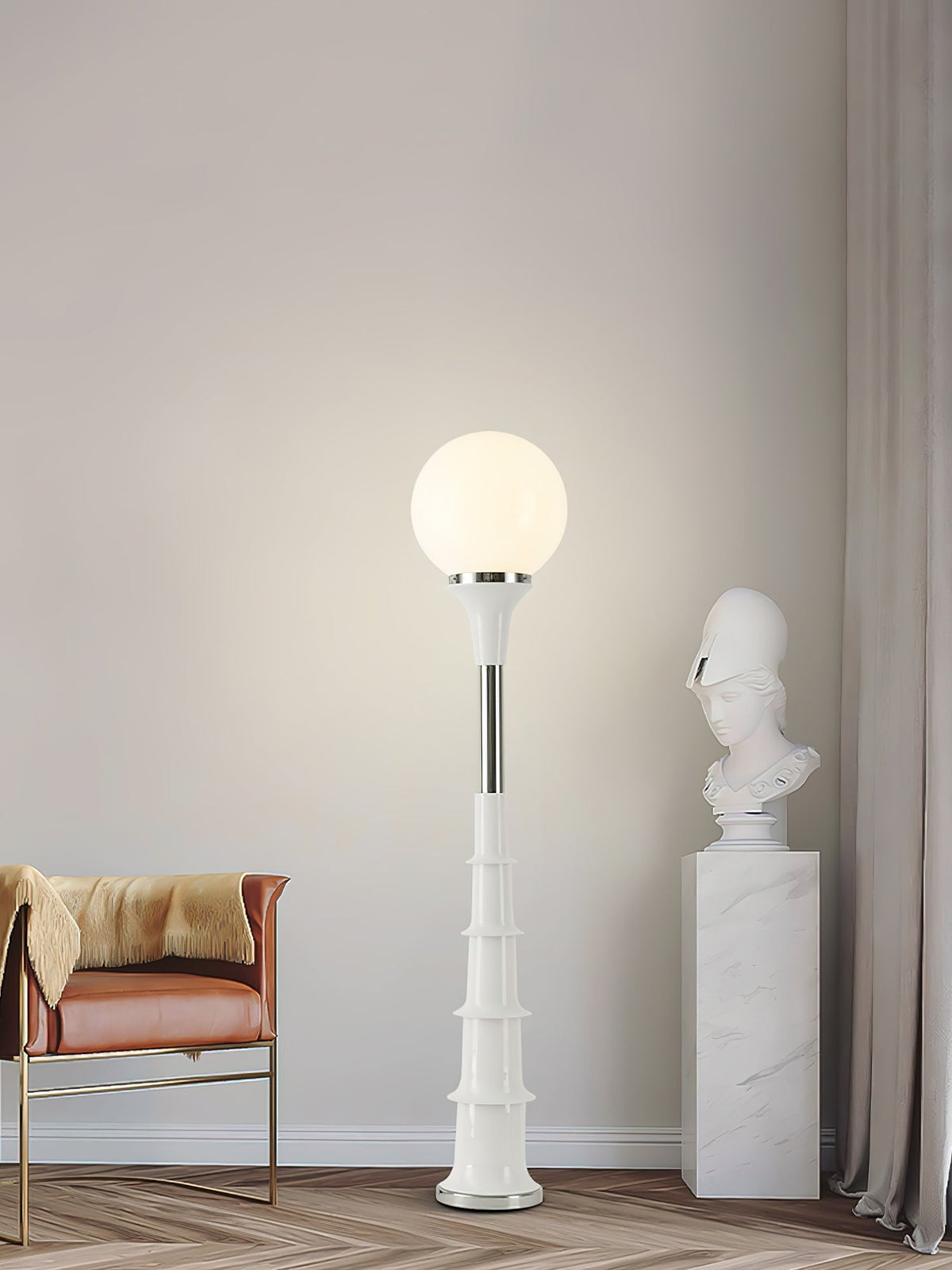 Clérachic floor lamp with a lit white globe and a cream ribbed stem, beside an orange leather chair and a marble bust.