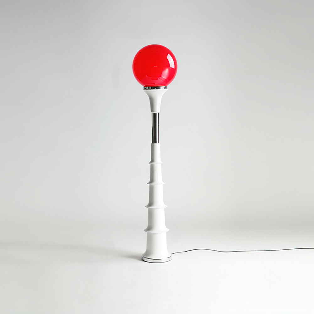 Red-globe Clérachic floor lamp with a white ribbed stem and chrome band, against a pale grey studio backdrop.