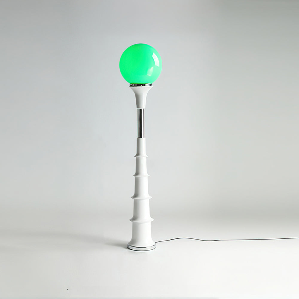 A Clérachic floor lamp with a green globe and white ribbed stem with a chrome band, on a plain studio backdrop.