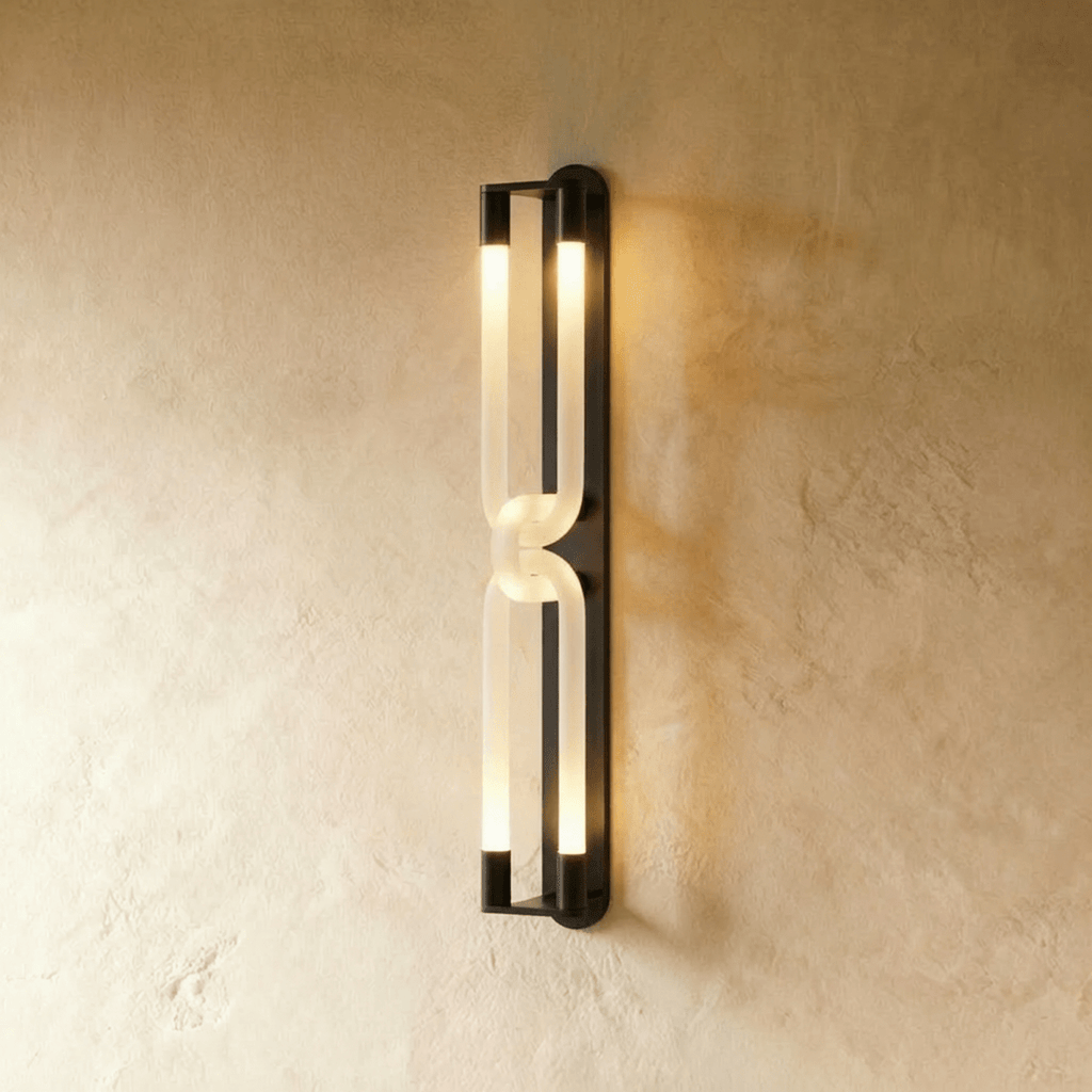 Clérachic tall wall light with two linked frosted loops and dark metal end caps, lit on a textured plaster wall.
