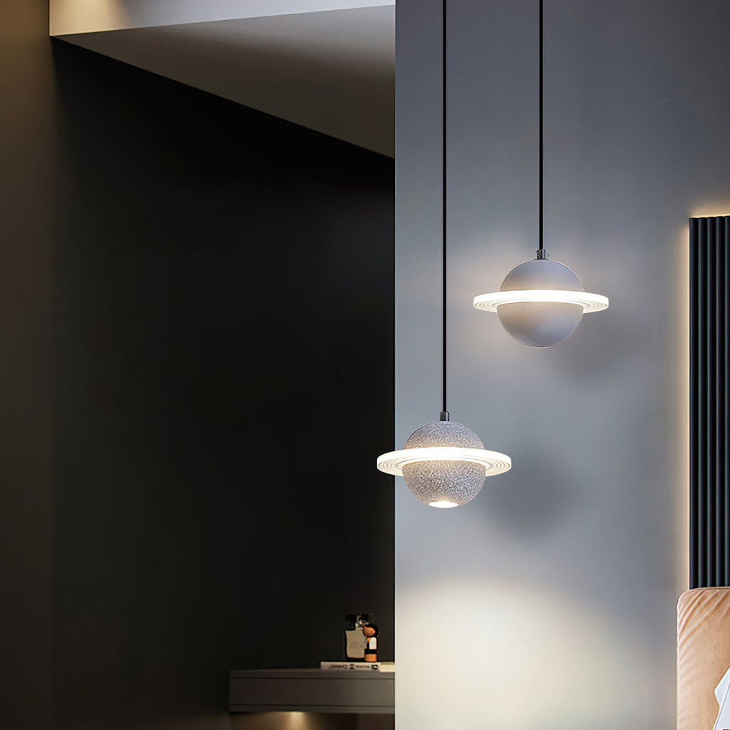 Two grey Clérachic planet pendants lit at different heights in a dark hallway beside a wall of black slats, with a warm glow below.