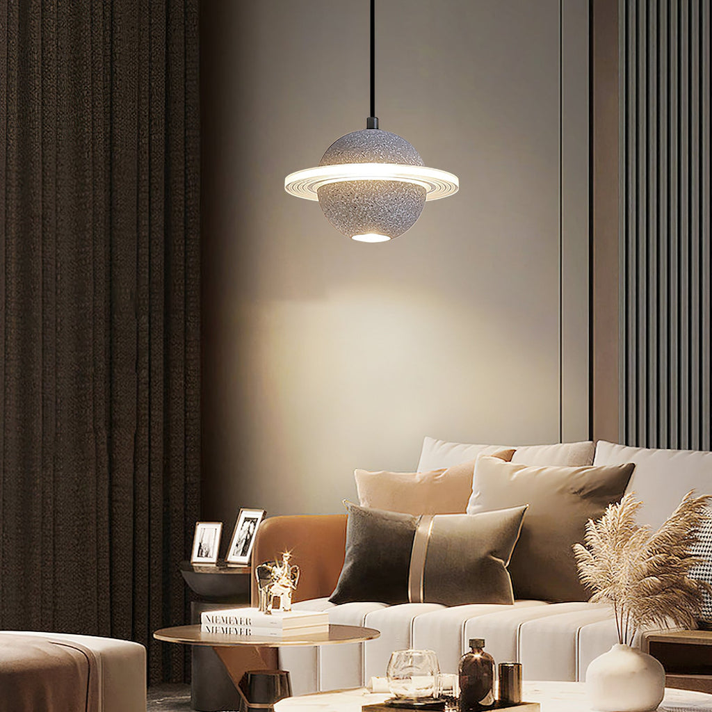 Clérachic pendant with a grey speckled sphere and ring lit in a living room with an orange sofa, cream cushions and dried pampas grass.