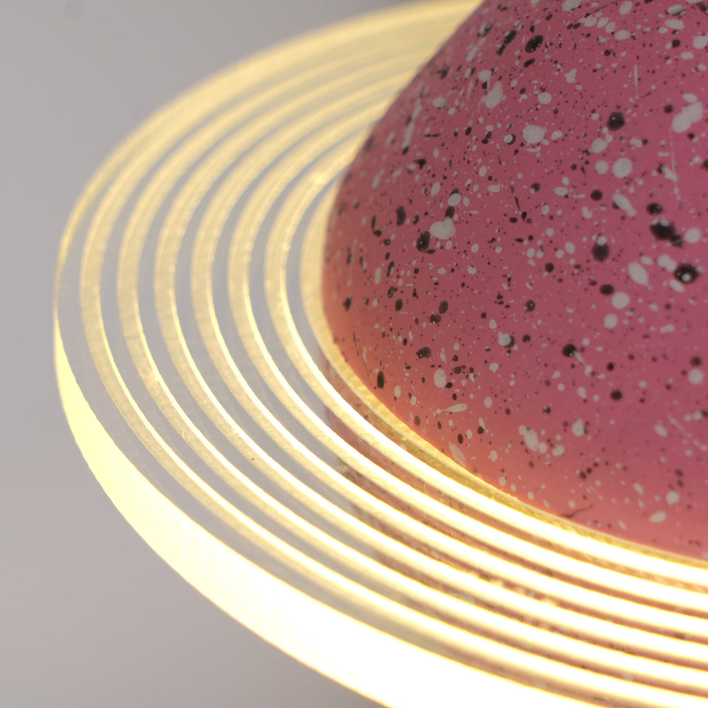 Close view of the concentric ridges in the glowing ring and the speckled pink surface of this Clérachic pendant.