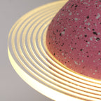 Close view of the concentric ridges in the glowing ring and the speckled pink surface of this Clérachic pendant.