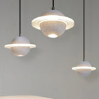 Three Clérachic planet pendants in grey and white hang at different heights against a grey wall, with glowing rings and downlights.