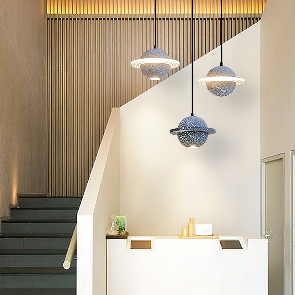 Clérachic planet pendants in grey blue and speckled blue hang above a stair landing with wood slats and a white reception counter.