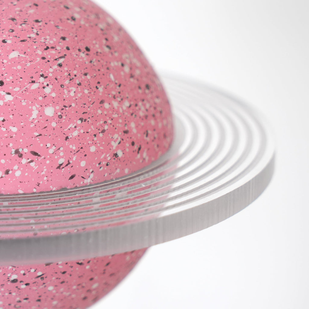 Close view of the clear ridged ring and white-and-black speckles on the pink sphere of this Clérachic pendant.