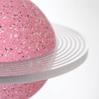 Close view of the clear ridged ring and white-and-black speckles on the pink sphere of this Clérachic pendant.