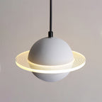 Lit grey Clérachic pendant with a smooth sphere and a glowing ridged ring, shown against a warm grey wall.