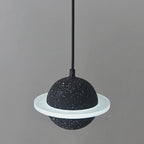 Black speckled sphere with a flat white ring, this Clérachic pendant unlit against a pale grey wall.