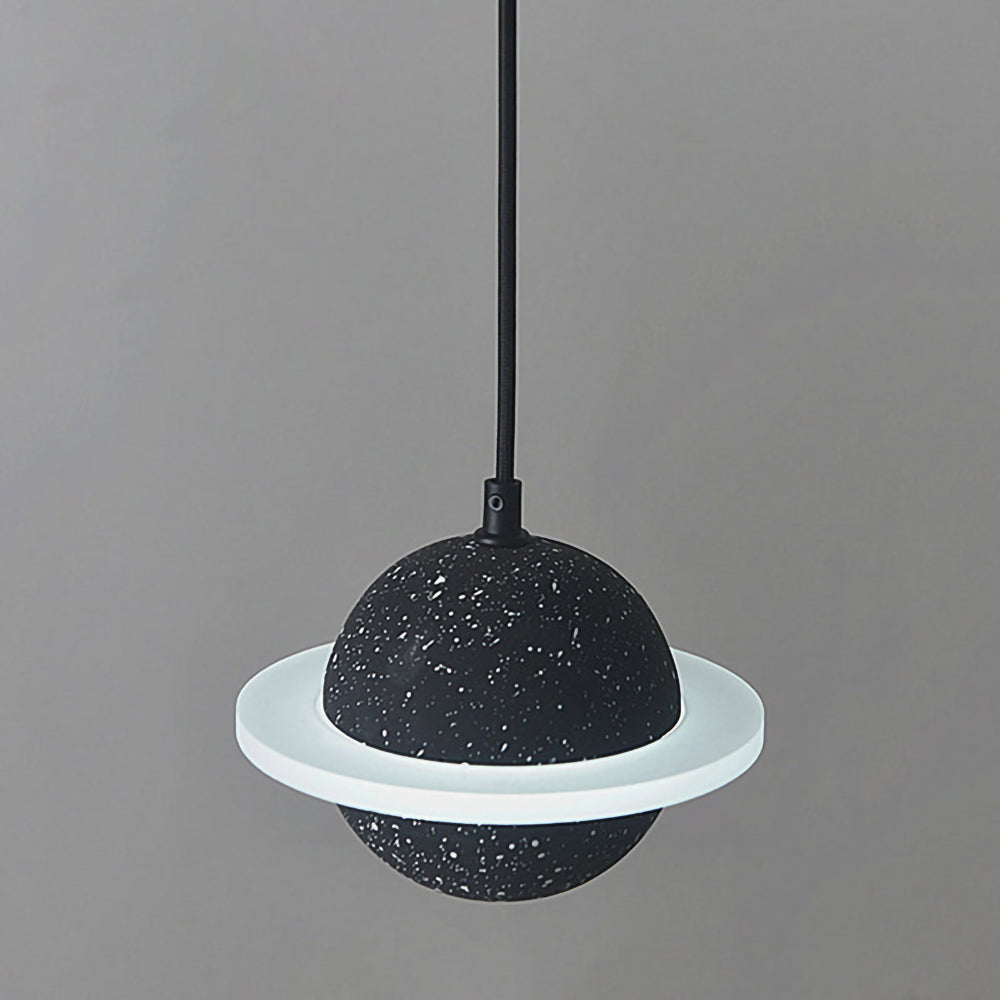 Black speckled sphere with a flat white ring, this Clérachic pendant unlit against a pale grey wall.