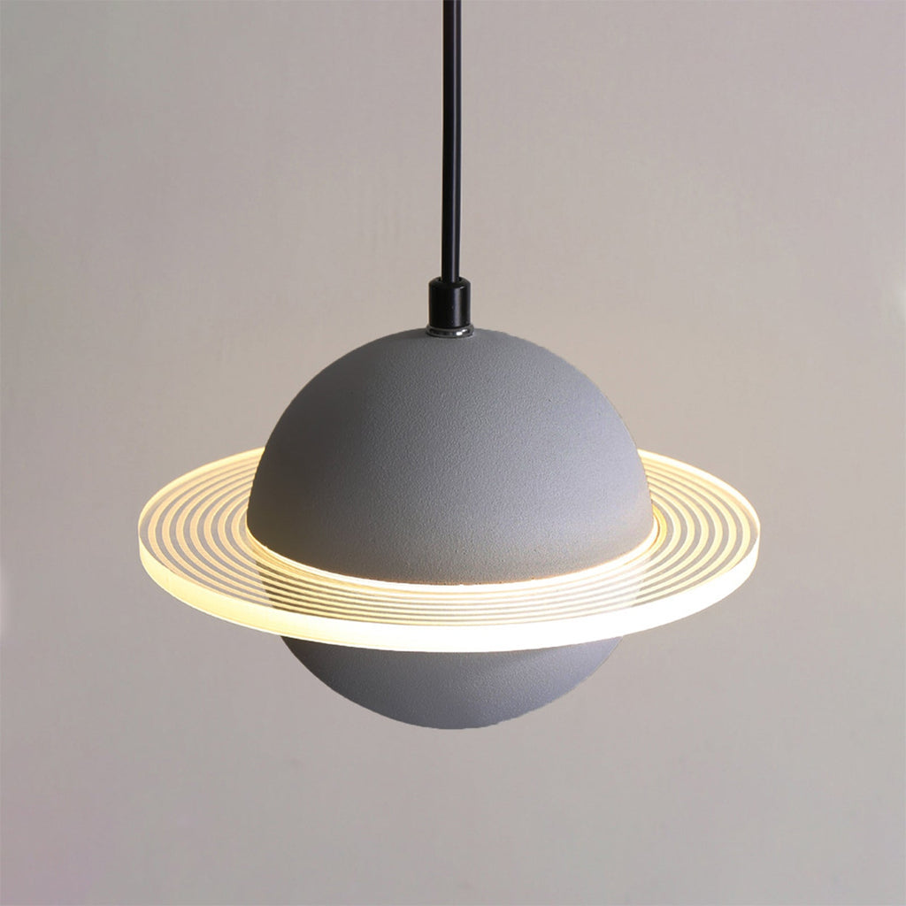 Straight-on view of a grey Clérachic pendant with a glowing ridged ring and a black cord against a soft grey wall.
