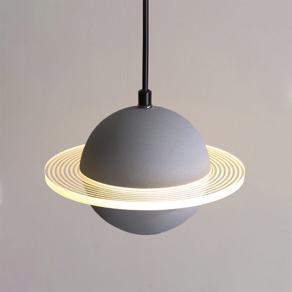 Straight-on view of a grey Clérachic pendant with a glowing ridged ring and a black cord against a soft grey wall.