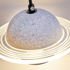 Close view of a pale grey terrazzo-style sphere and the glowing ridged ring of this Clérachic pendant, with a black cord at the top.