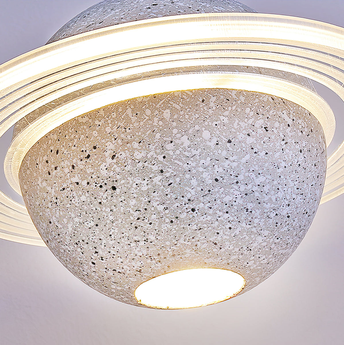 Looking up at the underside of a pale speckled Clérachic pendant, with a bright round bulb and a layered ring above.
