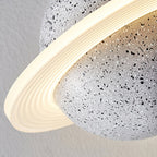 Close view of the ridged ring glowing around the black-and-white speckled sphere of this Clérachic pendant.