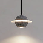 Lit sand black Clérachic pendant with a glowing ring and a spot of light below, against a warm grey wall.