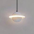 Pale speckled Clérachic pendant with a glowing ring and a soft halo on a grey wall, hanging on a black cord.