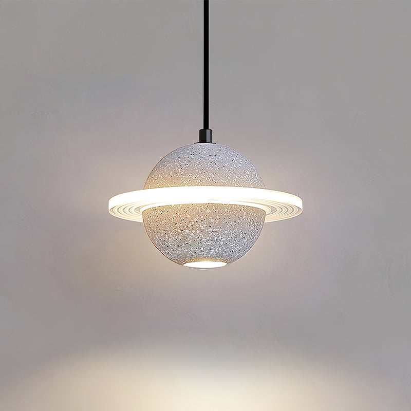 Clérachic pendant with a pale speckled sphere and a ridged glowing ring, throwing a pool of light down a grey wall.